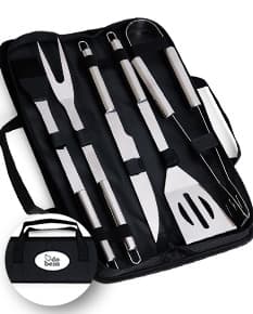 Kit Churrasco 5 Peças - Conjunto contendo faca, garfo, pinça, espátula e escova para churrasco em fundo de madeira.