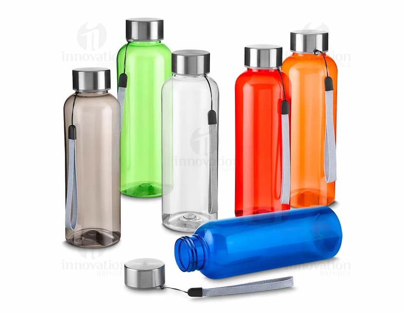 Garrafa plástica de 500ml em cor amarela, com tampa de metal e design transparente. A garrafa contém líquido e está próxima de um frasco de cremes e um frasco de perfume. A imagem mostra objetos de cuidados de higiene e beleza no banheiro.