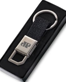 Chaveiro de couro preto com detalhes em metal prateado. Possui um suporte para celular e uma ferramenta cortante embutida. O chaveiro também conta com um display de tela digital, teclado e botões de conexão sem fio. É um acessório moderno e prático para negócios e comunicação.