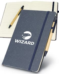 Caderneta de fibra de arroz com caneta em fundo branco. O caderno é marrom claro e possui detalhes em preto na capa. A caneta é de cor azul e está ao lado da caderneta.