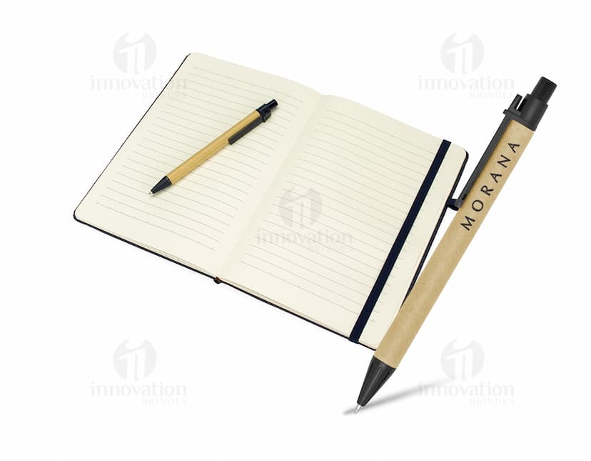 Caderneta de fibra de arroz com caneta em fundo branco. O caderno é marrom claro e possui detalhes em preto na capa. A caneta é de cor azul e está ao lado da caderneta.