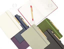 Rice fiber notebook with pen on a white background. The notebook is light brown with black details on the cover. The pen is