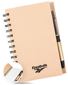 Caderno Ecológico com capa de papel kraft marrom, fecho de elástico e detalhe de folha verde. Páginas internas em papel reciclado.