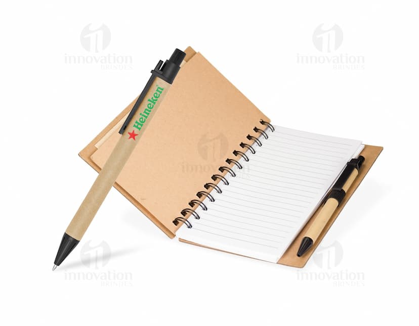 Caderno Ecológico com capa de papel kraft marrom, fecho de elástico e detalhe de folha verde. Páginas internas em papel reciclado.