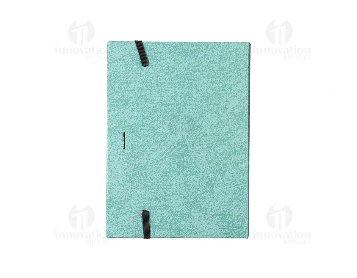 Bloco de anotações em papel reciclado com capa marrom e elástico azul, sobre uma mesa de madeira.