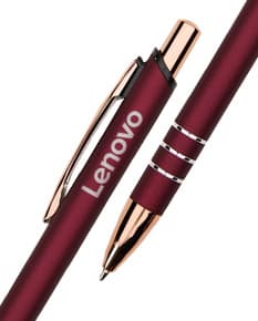 Caneta de metal prateada sobre um papel em branco, ao lado de um caderno de anotações e outros objetos de escritório.