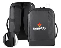 Homem de terno preto e pasta executiva, segurando uma mochila preta nas costas, em um ambiente corporativo.
