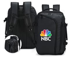 A smiling, well-dressed businessman holding a black leather backpack. He is standing in a studio and looks happy and