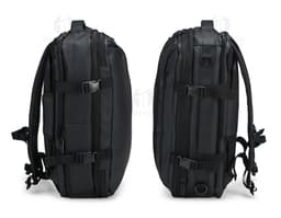 A smiling, well-dressed businessman holding a black leather backpack. He is standing in a studio and looks happy and