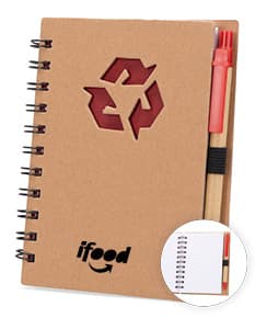 Caderno ecológico com caneta sobre uma mesa de escritório, ao lado de um papel em branco, uma mensagem escrita, um objeto de escritório e uma página de documento vazia. A imagem mostra um caderno vazio com espaço para escrever, ideal para anotações e lembretes no ambiente de trabalho.