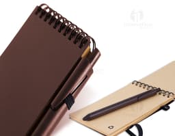 Bloco de anotações marrom com aroma de café de 70 folhas, sobre uma mesa de escritório. No bloco, é possível ver linhas para