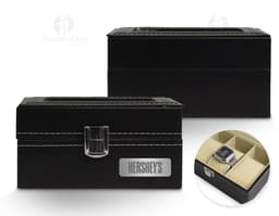 Caixa de couro preta contendo relógios, equipamento de gravação, dinheiro e objetos de valor.