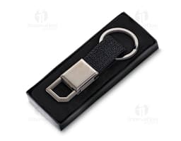 Chaveiro de couro preto com detalhes em metal prateado. Possui um suporte para celular e uma ferramenta cortante embutida. O