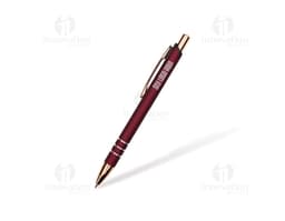 Bolígrafo de metal plateado sobre un papel en blanco, al lado de un cuaderno de notas y otros objetos de oficina.