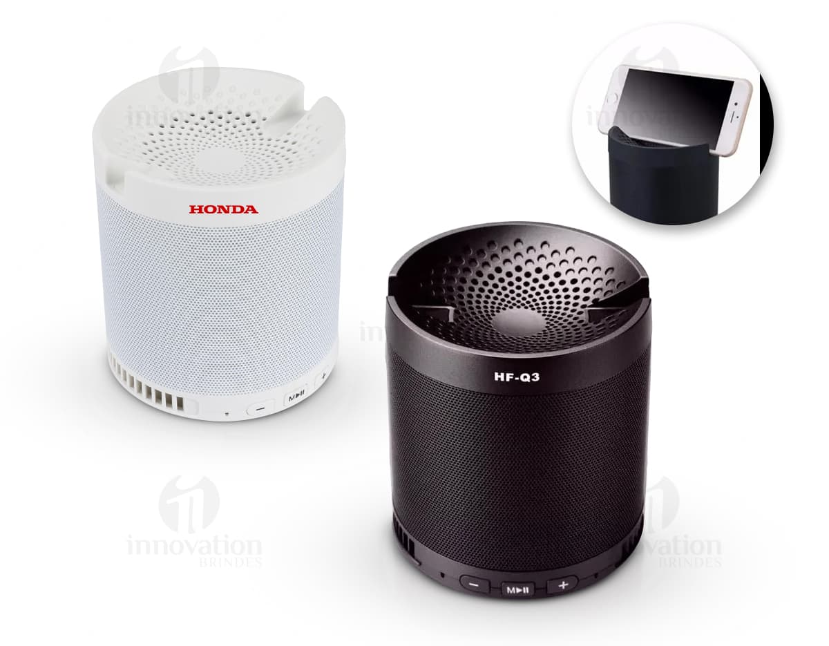 Caixa de som portátil com mosquetão em cor preta, possui botões de controle de volume e design compacto.
