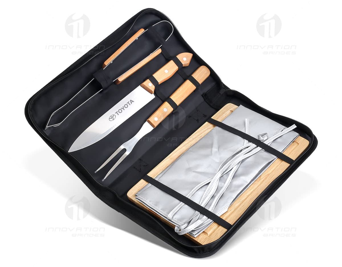 Kit churrasco em estojo com acessórios em fundo branco. O estojo contém faca, garfo, espátula, pinça e escova de limpeza, todos com cabo de madeira. Kit churrasco em estojo com acessórios em fundo branco. O estojo contém faca, garfo, espátula, pinça e escova de limpeza, todos com cabo de madeira.