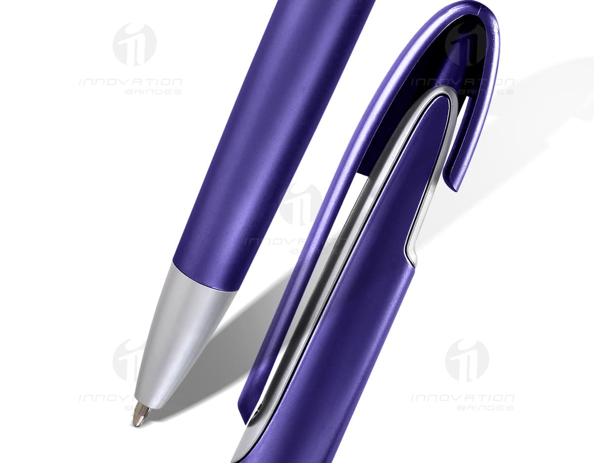 Mini caneta touch com suporte para celular em tom de prateado. Está sobre uma mesa de madeira clara, ao lado de um smartphone preto. Mini caneta touch com suporte para celular em tom de prateado. Está sobre uma mesa de madeira clara, ao lado de um smartphone preto.