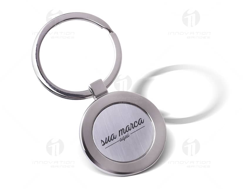 Chaveiro casa metal com design moderno em formato de casa, feito de metal prateado e brilhante. Possui detalhes em dourado e reflexo de vidro. Ideal para conectores e dispositivos tecnológicos.