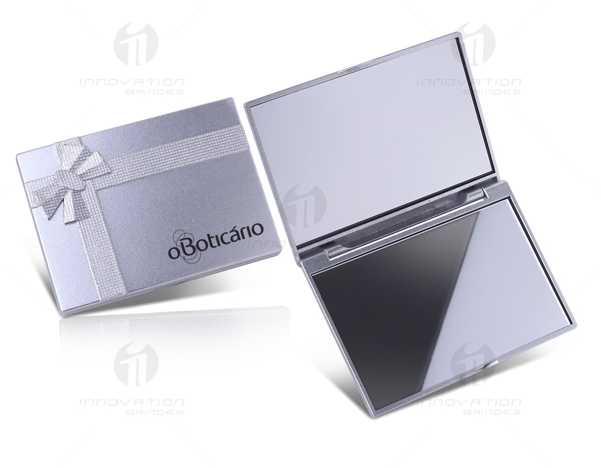 Espelho duplo de plástico com detalhes em preto e marrom, aberto e mostrando o reflexo de um notebook, modem, bloco de notas vazio e outros equipamentos eletrônicos. Espelho duplo de plástico com detalhes em preto e marrom, aberto e mostrando o reflexo de um notebook, modem, bloco de notas vazio e outros equipamentos eletrônicos.