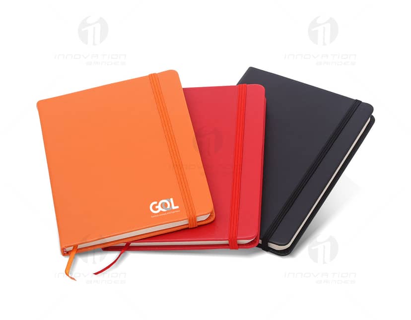 Caderno Elástico com Marca Páginas. Capa dura e elástico de fechamento na cor azul. O marca páginas é feito de fita azul.