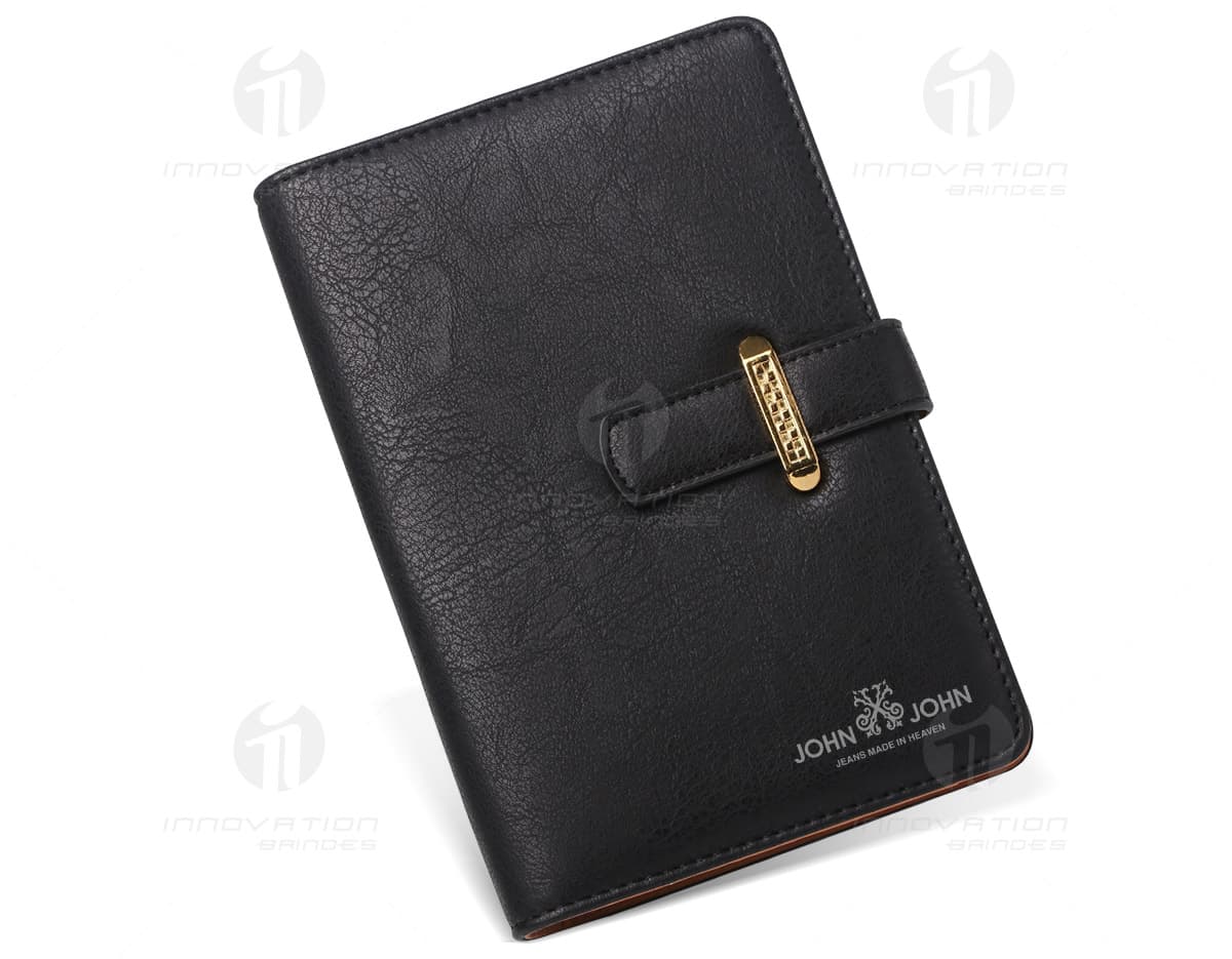 Caderno de couro marrom com capa e caneta prateada ao lado. Caderno de couro marrom com capa e caneta prateada ao lado.