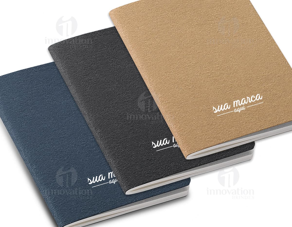 Bloco de anotações com capa dura de papel kraft aberto em uma mesa de madeira. Quatro canetas coloridas ao lado do bloco. Bloco de anotações com capa dura de papel kraft aberto em uma mesa de madeira. Quatro canetas coloridas ao lado do bloco.