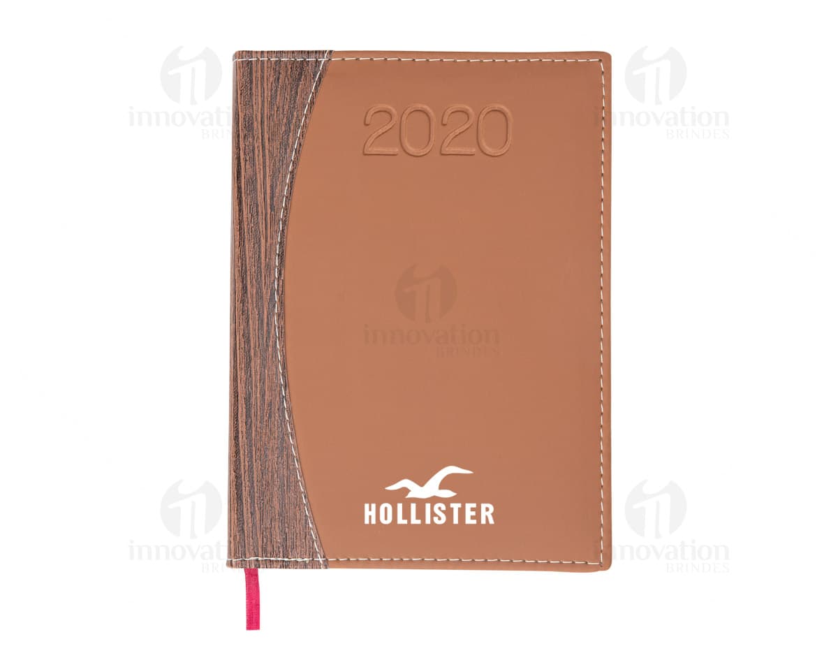Agenda 2021 com capa de couro marrom e folhas de papel branco aberta mostrando mês de janeiro e uma caneta ao lado. Agenda 2021 com capa de couro marrom e folhas de papel branco aberta mostrando mês de janeiro e uma caneta ao lado.
