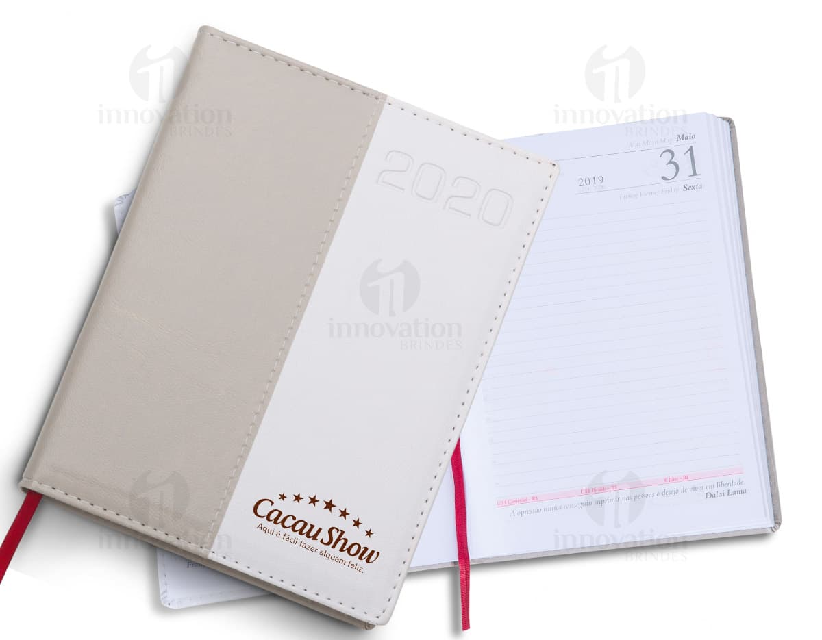 Agenda 2020 aberta, mostrando páginas em branco com design vintage e espaço para anotações. Capa marrom envelhecida, com uma caneta no topo. Agenda 2020 aberta, mostrando páginas em branco com design vintage e espaço para anotações. Capa marrom envelhecida, com uma caneta no topo.