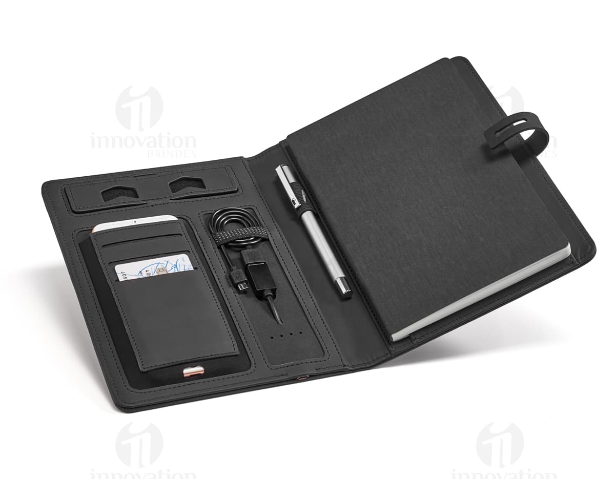 Pasta A5 com carregador portátil em cor preta, feita de material resistente e com compartimento específico para armazenar o carregador. Pasta A5 com carregador portátil em cor preta, feita de material resistente e com compartimento específico para armazenar o carregador.