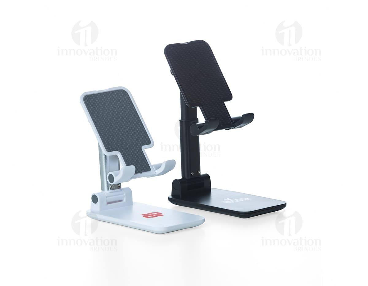 Suporte retrátil para celulares em cor preta. O suporte está fixado em uma mesa e possui ajuste de tamanho para diferentes modelos de celulares. Suporte retrátil para celulares em cor preta. O suporte está fixado em uma mesa e possui ajuste de tamanho para diferentes modelos de celulares.