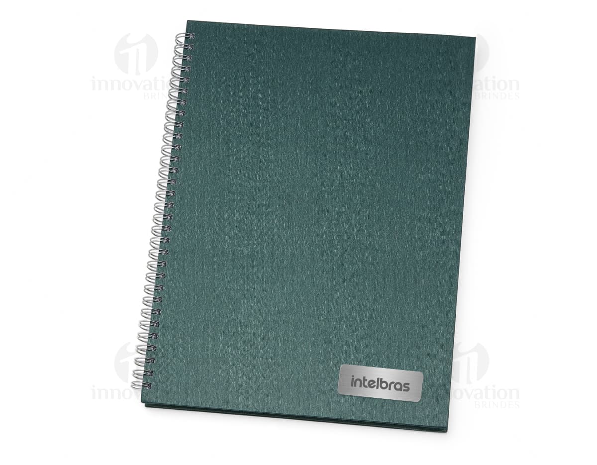 Kit de Caderno e Caneta em fundo branco. O caderno possui capa verde com elástico e a caneta é azul. Kit de Caderno e Caneta em fundo branco. O caderno possui capa verde com elástico e a caneta é azul.