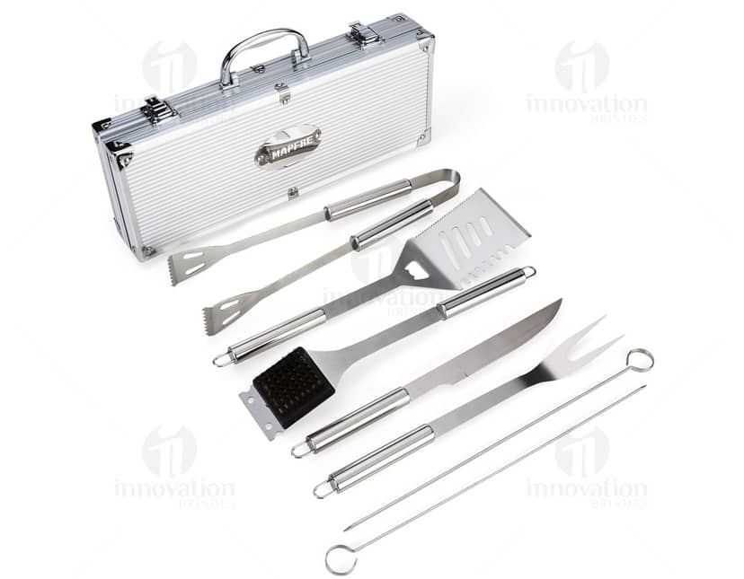 Kit churrasco composto por 7 peças em uma caixa de metal. Inclui faca, garfo, avental, luva, pegador, saleiro e pimenteiro.