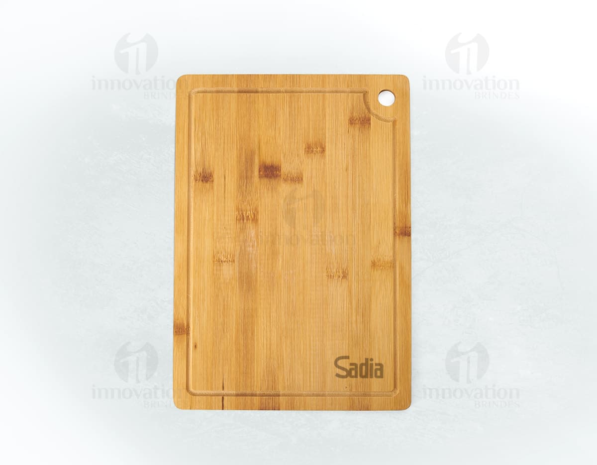 Tábua de corte retangular com gancho e canaleta, ideal para preparar alimentos de forma prática e segura. A tábua parece ser feita em madeira e tem um design moderno. Tábua de corte retangular com gancho e canaleta, ideal para preparar alimentos de forma prática e segura. A tábua parece ser feita em madeira e tem um design moderno.
