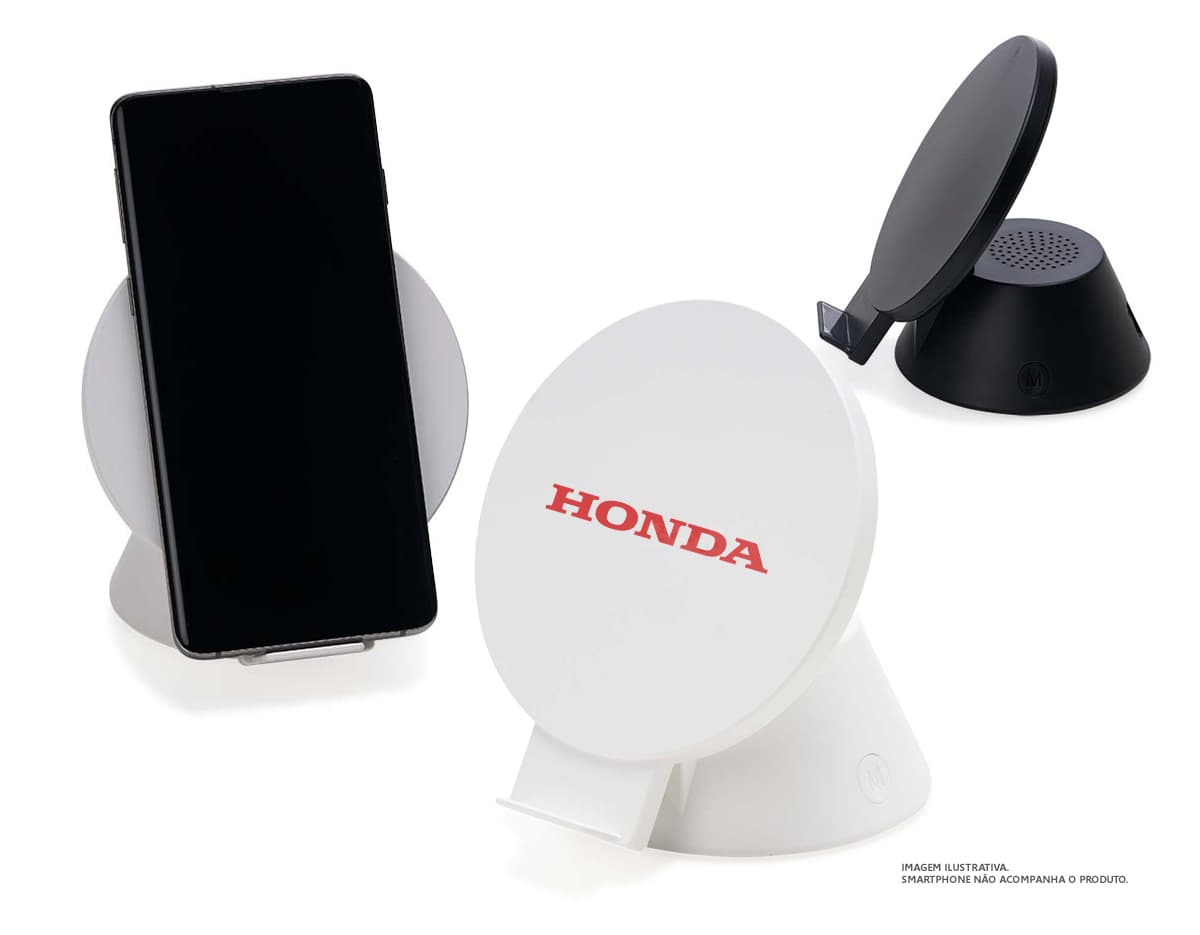 Caixa de som preta e brilhante com carregador por indução, ao lado de um computador e outros dispositivos eletrônicos. Caixa de som preta e brilhante com carregador por indução, ao lado de um computador e outros dispositivos eletrônicos.
