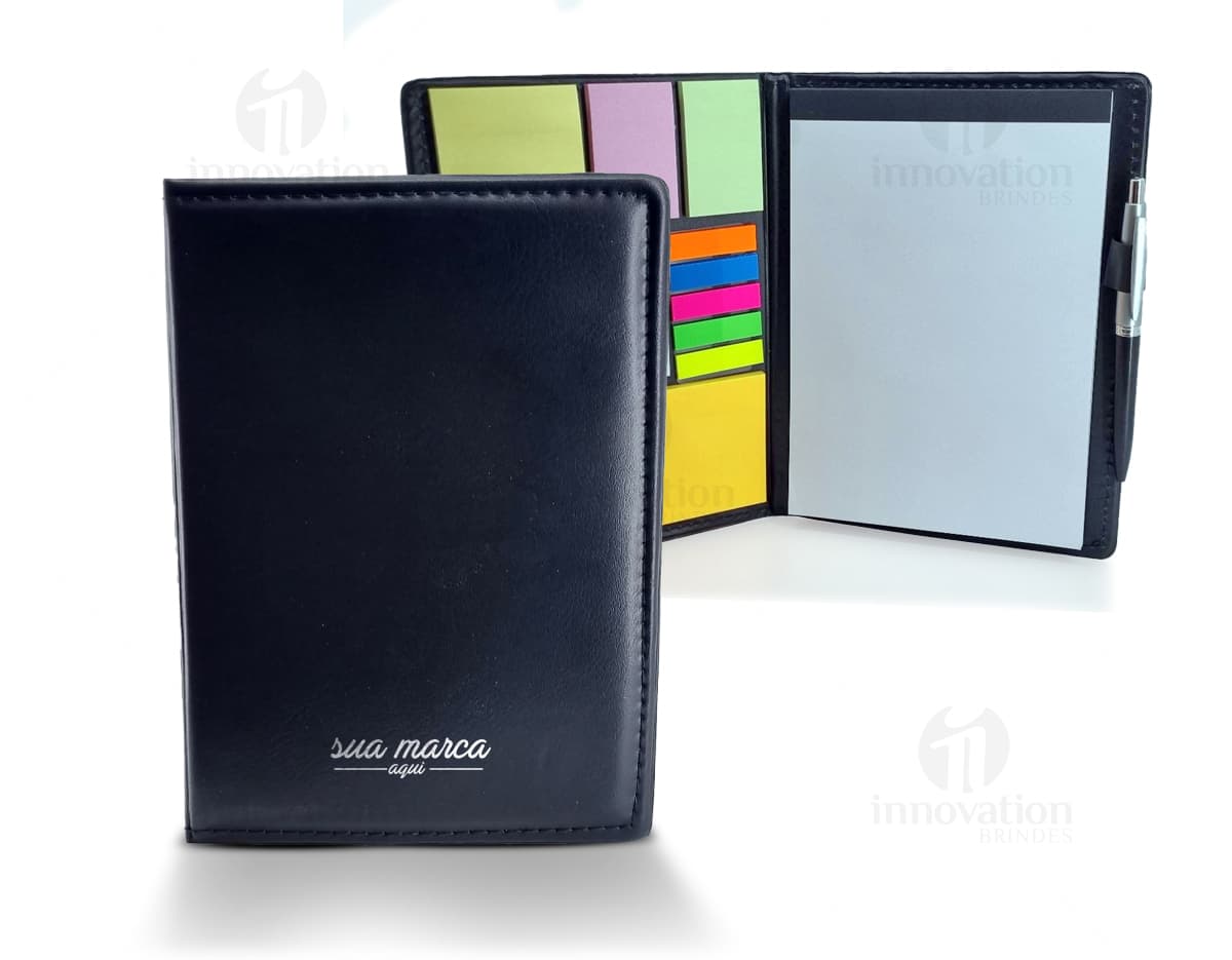 Bloco de anotações aberto com várias folhas coloridas e autoadesivos em cima de uma mesa de madeira clara. Bloco de anotações aberto com várias folhas coloridas e autoadesivos em cima de uma mesa de madeira clara.