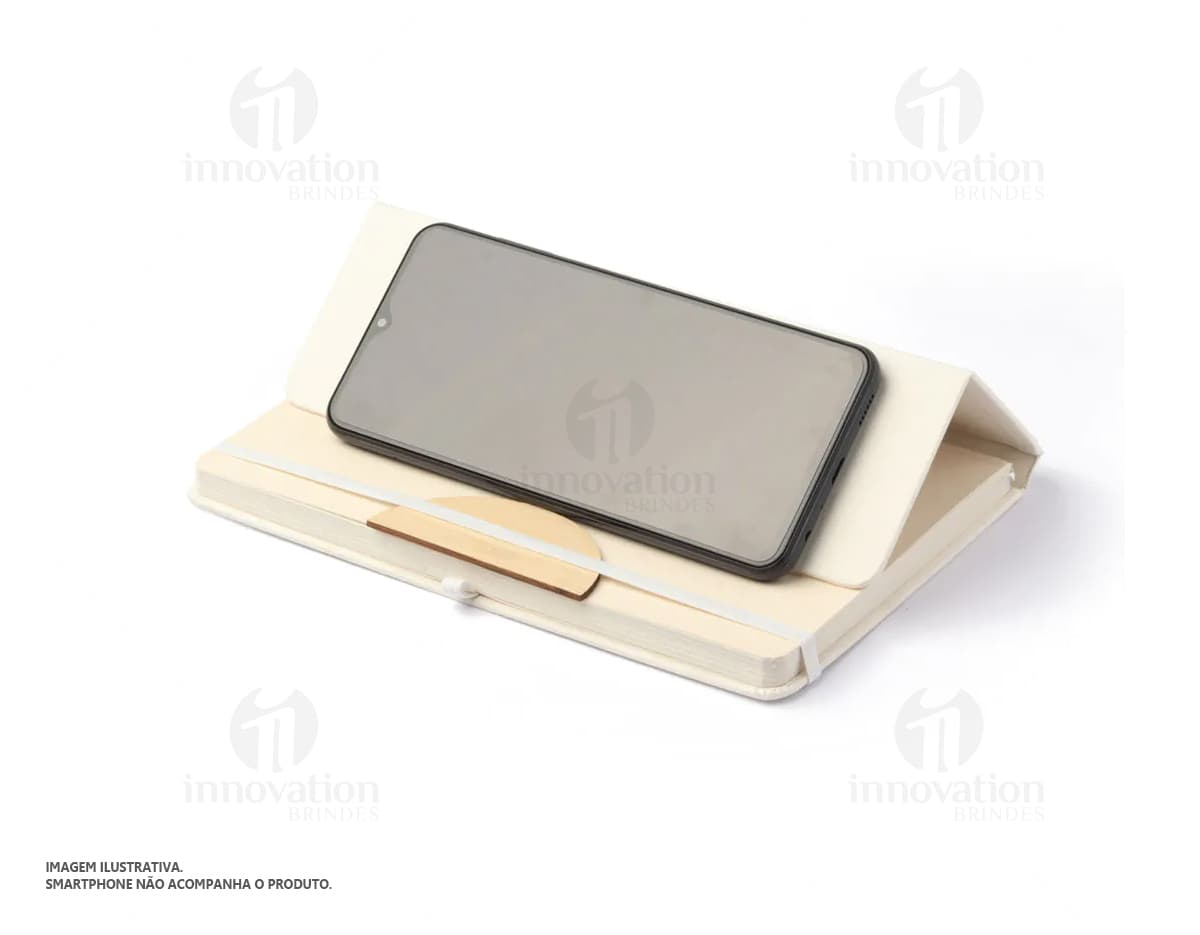 Bloco de anotações com suporte para smartphone em cor preta. O bloco está aberto com algumas páginas visíveis e ao lado há um smartphone encaixado no suporte, exibindo a tela inicial. Bloco de anotações com suporte para smartphone em cor preta. O bloco está aberto com algumas páginas visíveis e ao lado há um smartphone encaixado no suporte, exibindo a tela inicial.