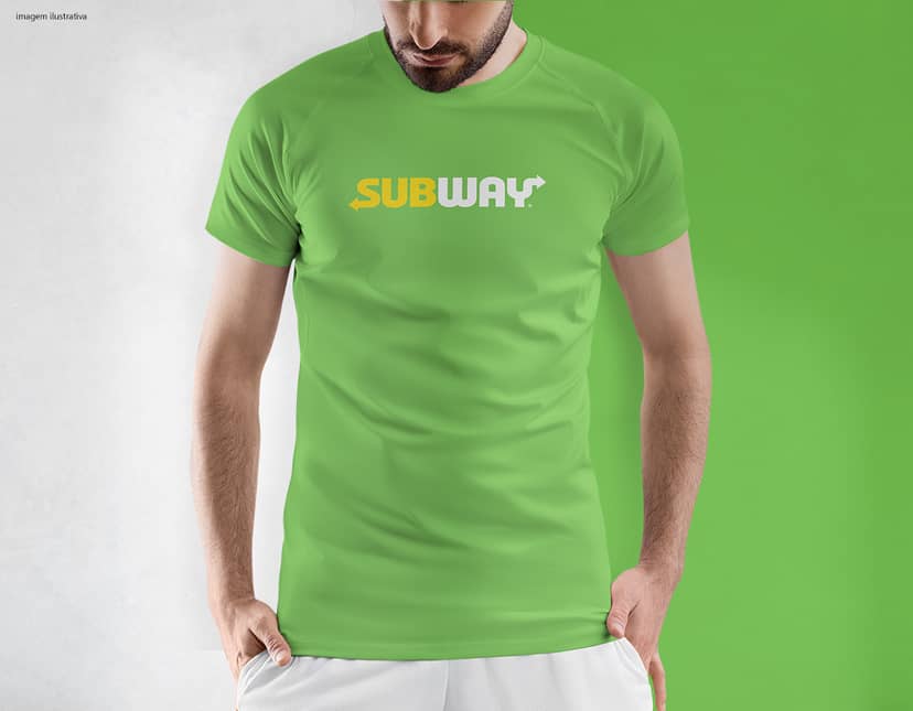 Homem jovem e atraente usando uma camiseta preta tradicional, sorrindo de forma confiante e casual. Ele está em pé, posando para a câmera em um estúdio, com um estilo moderno e esportivo. O modelo é magro e está em forma, transmitindo uma imagem de saúde e sucesso.