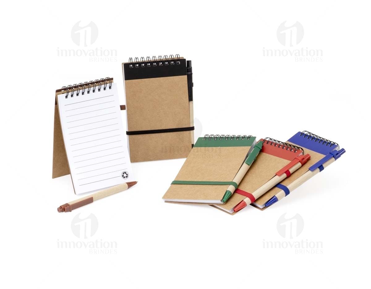 Bloco de anotações 14x9 em papel pautado, cor creme, com capa dura azul-marinho e elástico para fechar. Na capa, há o logo da marca em dourado. Bloco de anotações 14x9 em papel pautado, cor creme, com capa dura azul-marinho e elástico para fechar. Na capa, há o logo da marca em dourado.