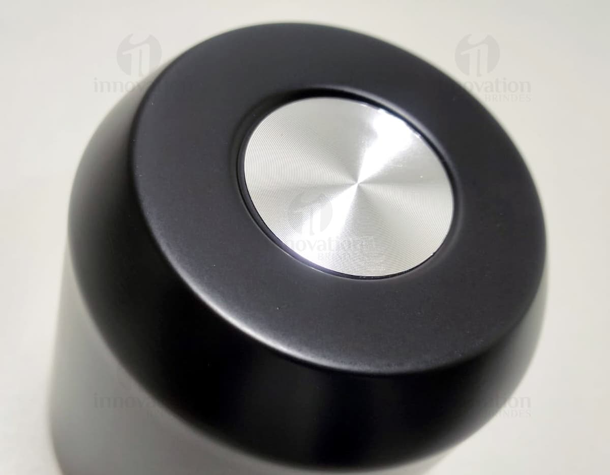 Copo térmico de 280ml em cerâmica preta e metal de cor prateada, com alça e tampa. O copo está vazio e posicionado sobre uma mesa de cozinha, ao lado de uma colher, uma jarra de café e alguns utensílios. Copo térmico de 280ml em cerâmica preta e metal de cor prateada, com alça e tampa. O copo está vazio e posicionado sobre uma mesa de cozinha, ao lado de uma colher, uma jarra de café e alguns utensílios.